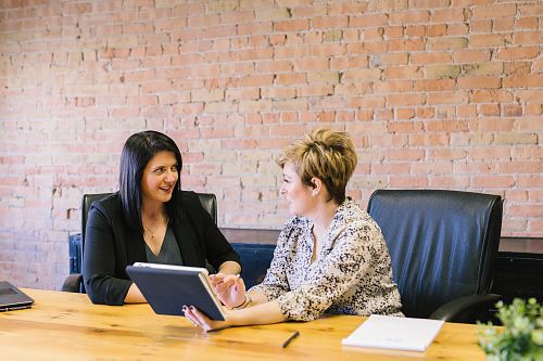 two women sitting on leather chairs in front of table
