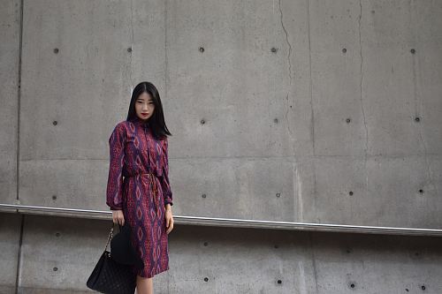 woman holding bag standing beside wall