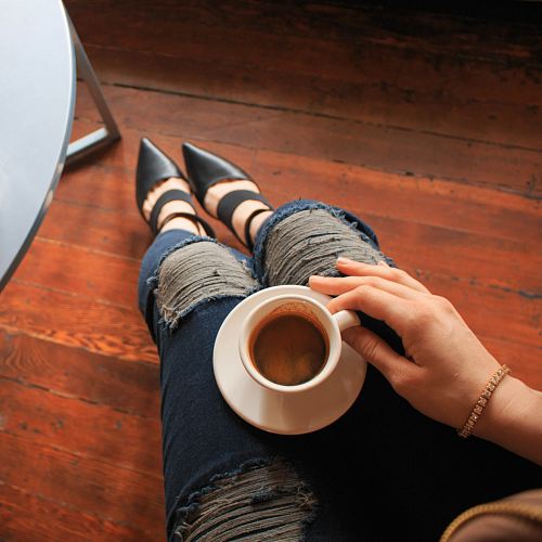 woman holding coffee cup on white saucer plate