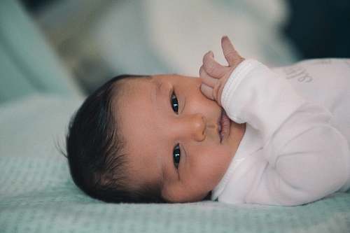 human baby in white shirt lying on bed person