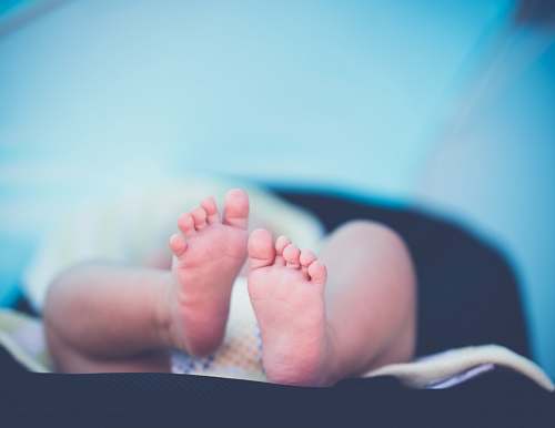 newborn shallow focus photography of baby wearing white diaper lying child