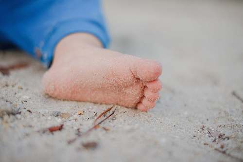 sand shallow focus photography of toddler's foot with sand sandy