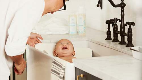 human smiling baby in sink beside smiling person person