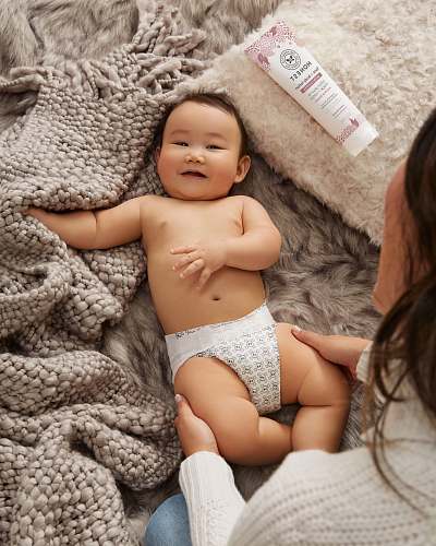 diaper smiling toddler in grey and white diapers lying on bed newborn