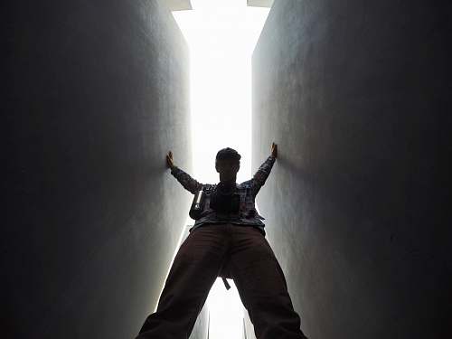 person low-angle photo of man standing between walls lighting