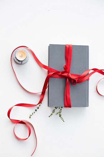 gift gray book wrapped with red ribbon beside teallight candle red