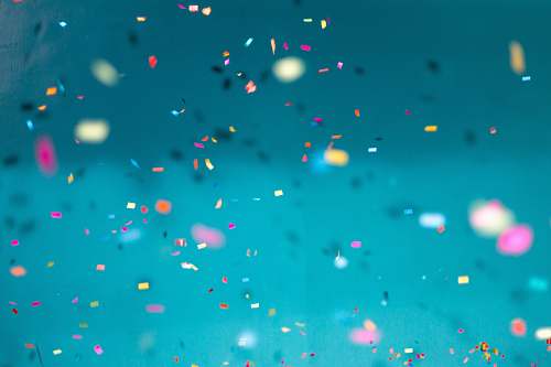 blue selective focus photography of multicolored confetti lot background