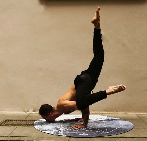 yoga man doing stunt near brown wall exercise