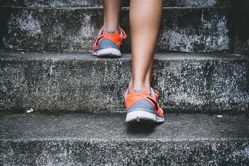 people person wearing orange and gray Nike shoes walking on gray concrete stairs sport