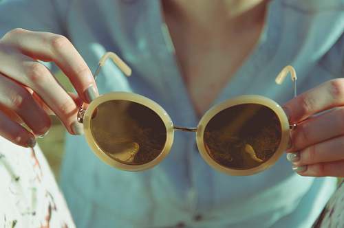 sunglasses woman holding round sunglasses during daytime retro