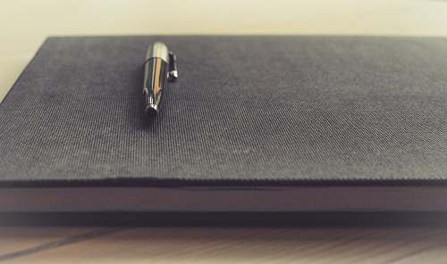 pen gray click pen on black book notebook