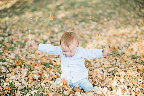 person baby on ground with dried leaves leaf