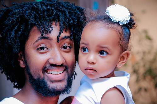 person man in white top holding girl baby people