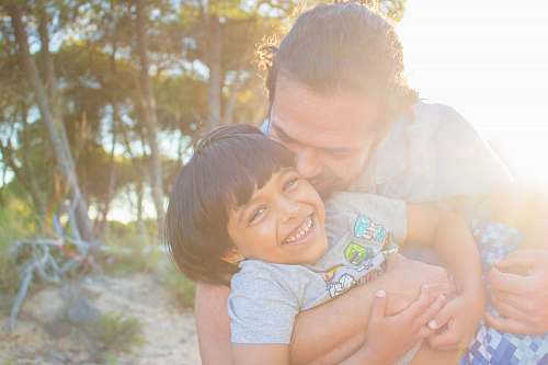person man kissing child during golden hour hug