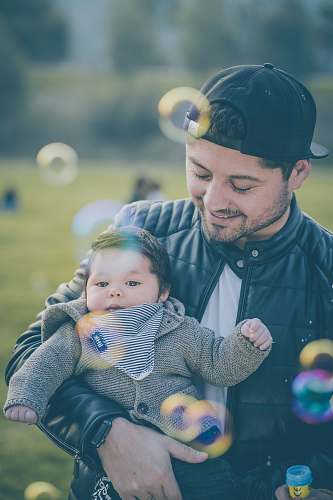 apparel man wearing black jacket carrying baby clothing
