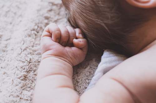 person newborn baby lying down on brown blanket people