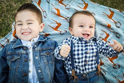 person two boys laying on blue textile people