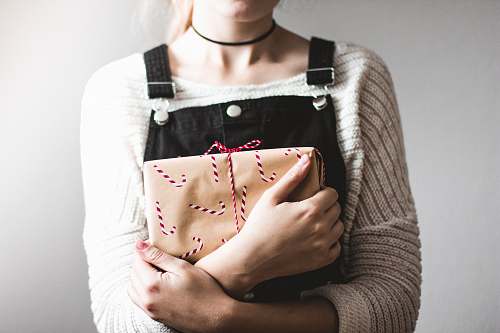 person woman wearing grey sweater and black overall pants while holding brown bag people