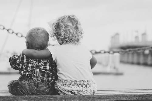black-and-white grayscale photography of two children sitting on ledge grey