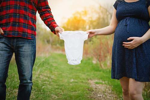 human both man and woman holding baby's white onesie person
