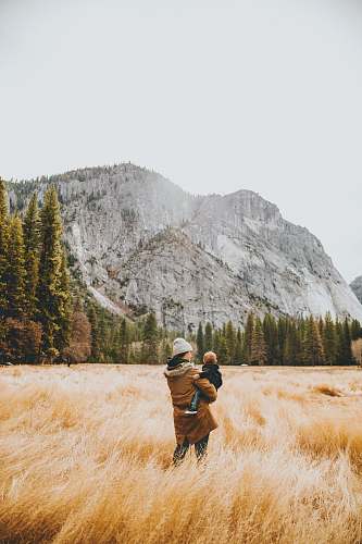 person person standing on grass field while carrying child human