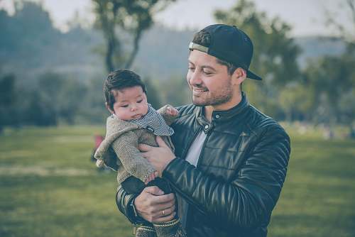 apparel man wearing black leather jacket holding baby clothing