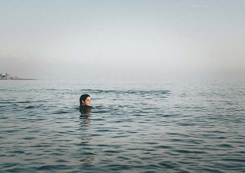 swimming person on body of water during daytime sport
