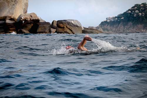 human person swimming across brown rocks sport