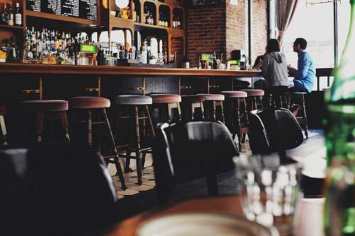people two person sitting on bar stool chair in front of bar front desk restaurant