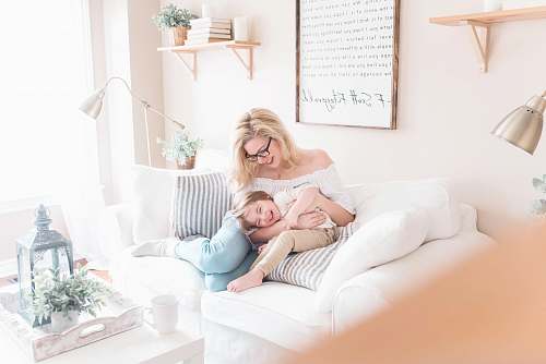 human woman and baby sitting on white sofa furniture