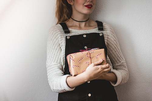 people woman carrying brown leather bag while standing near white painted wall human