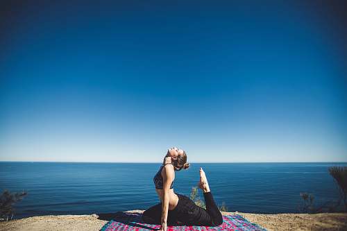 people woman wearing black top and pants stretching body on mat yoga