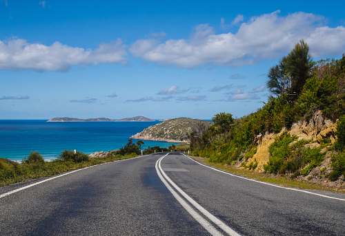 water curved road near cliff sky