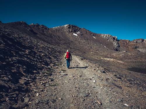 gravel man standing beside rock mountain dirt road