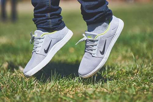 shoe pair of gray Nike low-top sneakers hanging on green grass spring