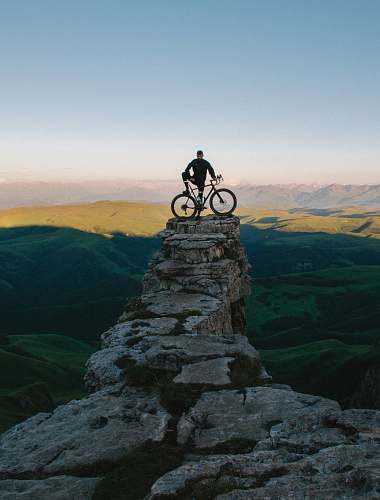 bicycle man holding bike while standing on gray mountain bike