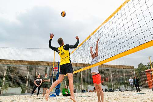 human man wearing yellow and black long-sleeved shirt playing volleyball team sport