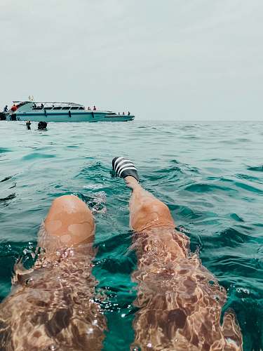 human person swims near yacht person