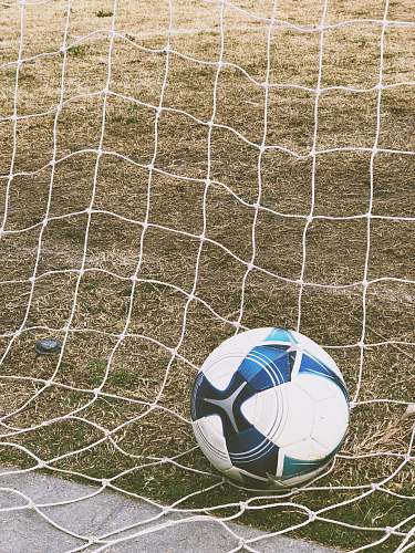 soccer white and blue soccer ball on ground inside goal soccer ball
