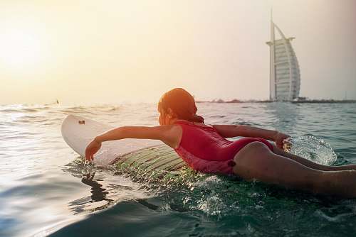 surfboard girl on top of white surfboard beside Burj Al Arab sport