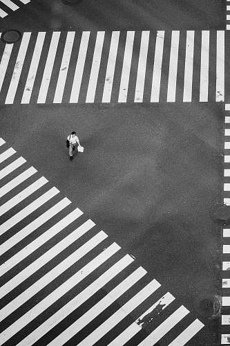 asphalt man walking at the center of crisscrossing pedestrian lanes black-and-white