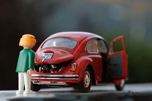 car orange hair Lego toy looking at red beetle car toys