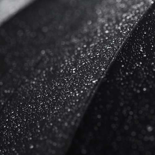 black-and-white Macro shot of tiny droplets of water on a black surface water drop