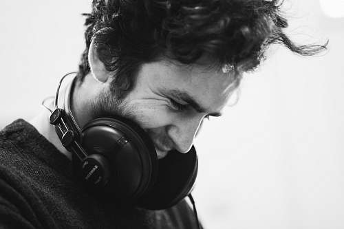 human grayscale photography of man with headphones on neck headphones