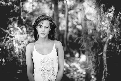 people grayscale photography of woman standing front of forest human