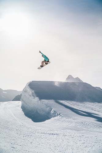 sport man in black jacket and blue denim jeans jumping on snow covered mountain during daytime human