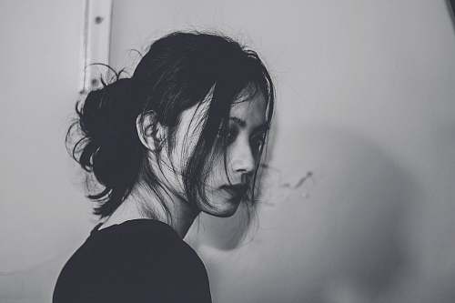 human grayscale photography of woman standing near wall grey