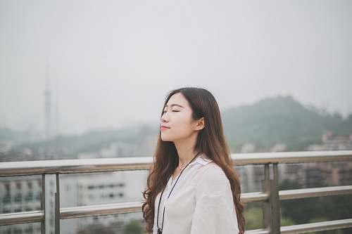 woman woman closing eyes white standing against stainless steel rail person