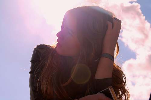 human woman in black top holding her hair looking up person