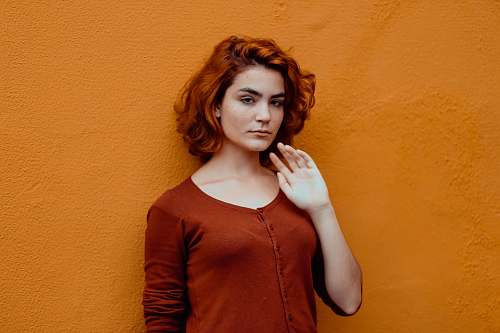 person woman in red button-up shirt leaning orange wall human